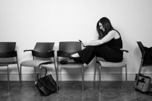 Woman seated on a chair in a cosmetic dermatology clinic, photographed inside Kamloops Skin Solutions with a relaxed posture and natural light.