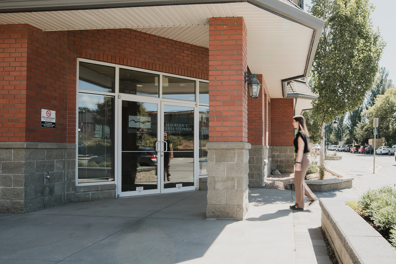 Exterior entrance of Kamloops Skin Solutions clinic with a client walking toward the front doors in daylight.